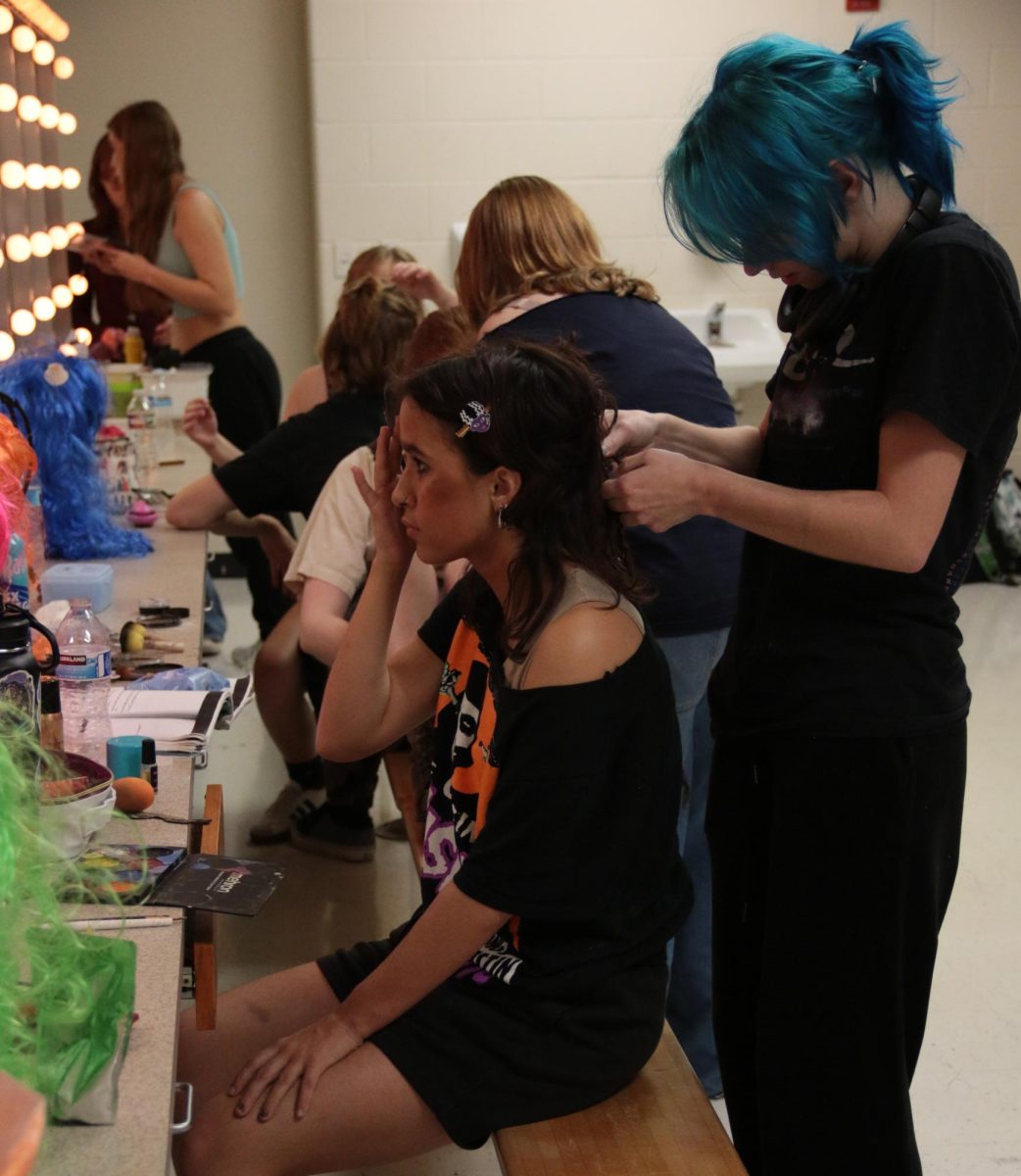 Hair and makeup crew member, Avery Applegate, creates the perfect hairdo for Chanse Solis who played Black Stache.