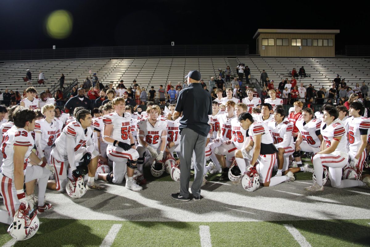 Varsity huddles together after their win against Cedar Ridge, their coach gives them a congrats speech.