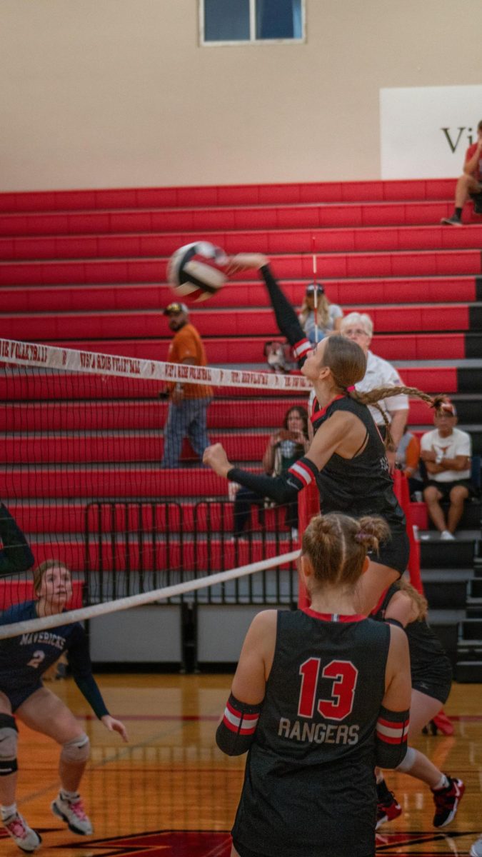 Sophomore Opposite Hitter Abby Norling spikes the ball through the McNeil defensive wall taking the point for the Lady Rangers.
