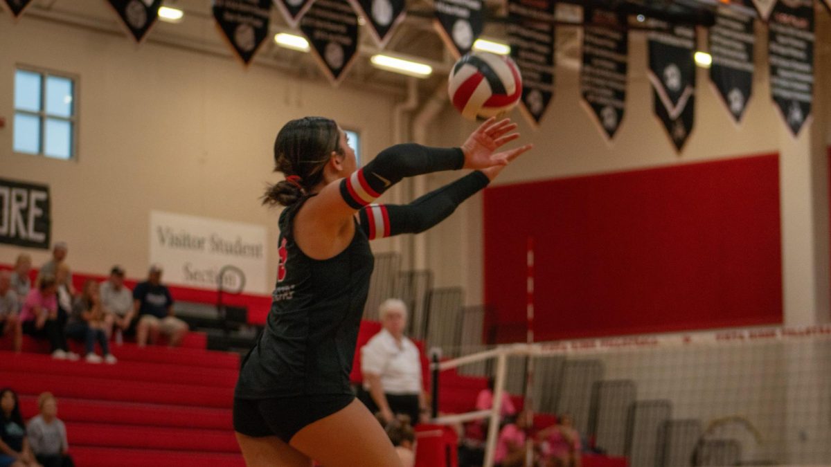 Junior Defensive Specialist Danica Puepke toss the ball in the air while staying low to charge up a powerful serve to oppress the McNeil Volleyball team. 