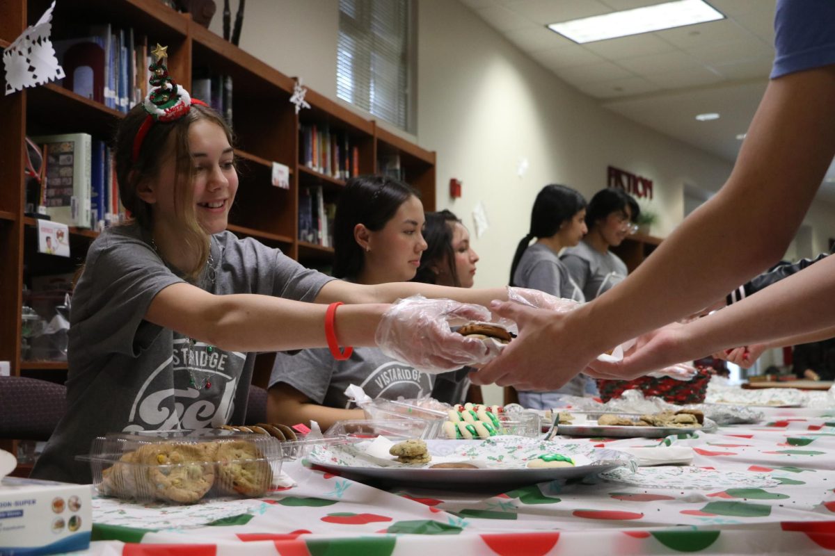 Sophomore Olivia Esselman hands out cookies in the library for students to eat last year for Blue Santa.