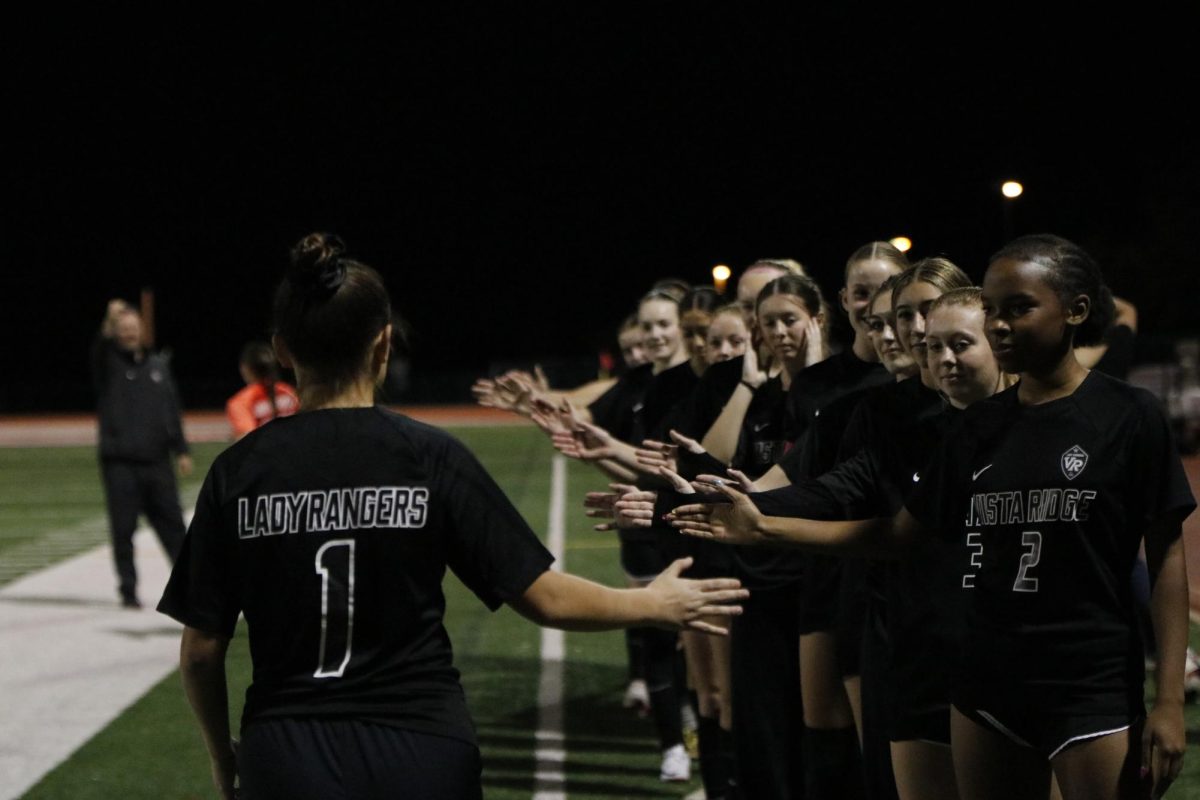 While getting her name called, junior Arden Tutor runs down the field while high fiving her teammates